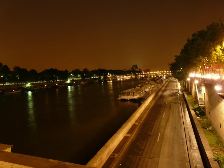 night view from the top of a bridge with boats parked along the street and buildings to the side