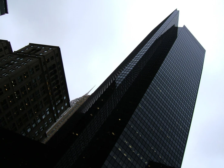 looking up at two black skyscrs against a gray sky