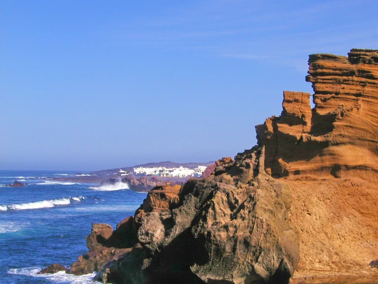 a scenic rocky cliff overlooking the ocean with a view of the city and the beach