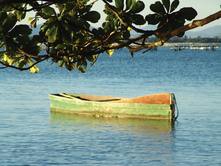 small wooden boat anchored up in the water on a sunny day
