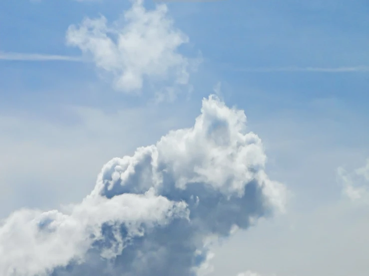 an airplane flying through a blue sky with white clouds