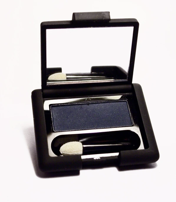 the compact eye shadow in black is resting on its container