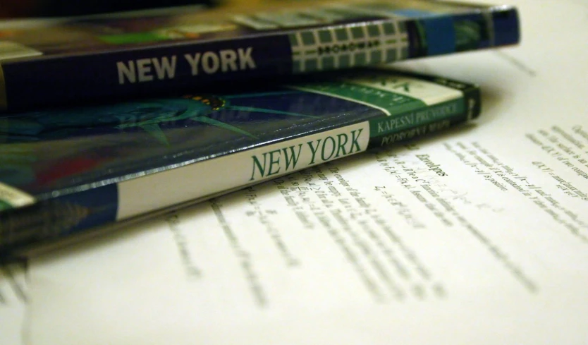 two new york books sitting on a table next to an open letter of paper