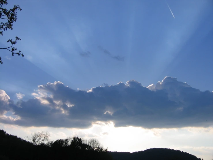 there is sun shining in a cloud above some hills