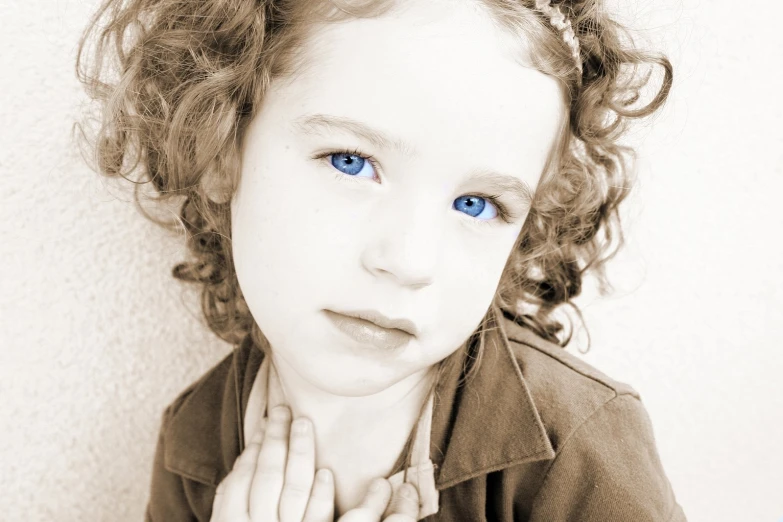 a young child with blue eyes sitting in front of a wall