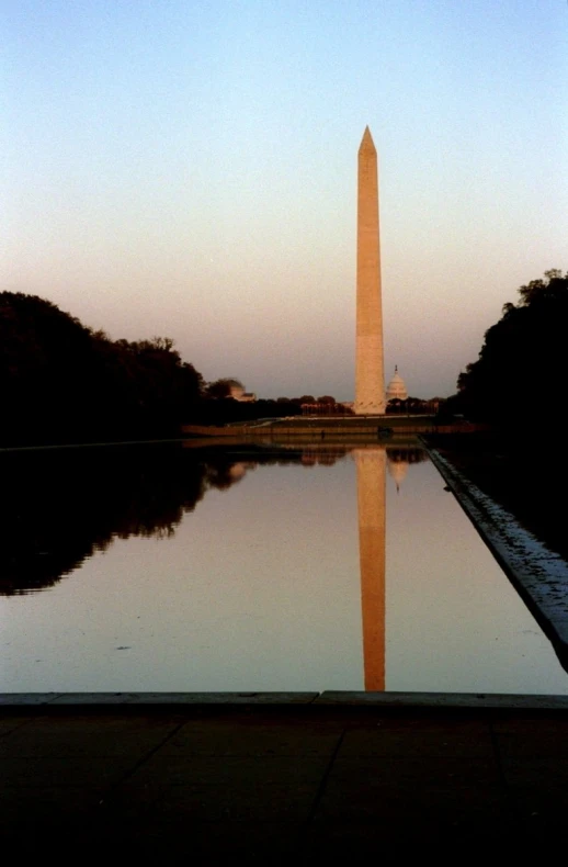 the washington monument stands tall at the end of a reflecting pool
