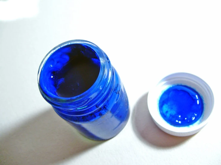 a blue bottle sitting on top of a table next to a blue container