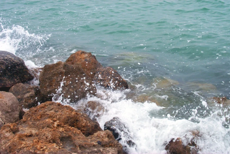 water splashes over large rocks on the beach