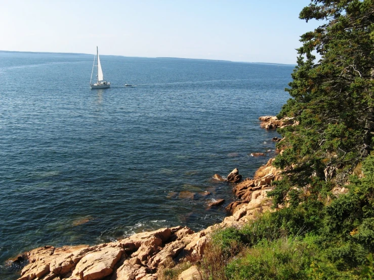 a sailboat sailing on the ocean near rocks