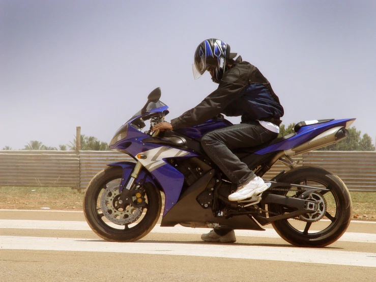 a man riding on the back of a blue motorcycle