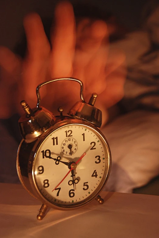 an alarm clock sitting on top of a bed next to some sheets