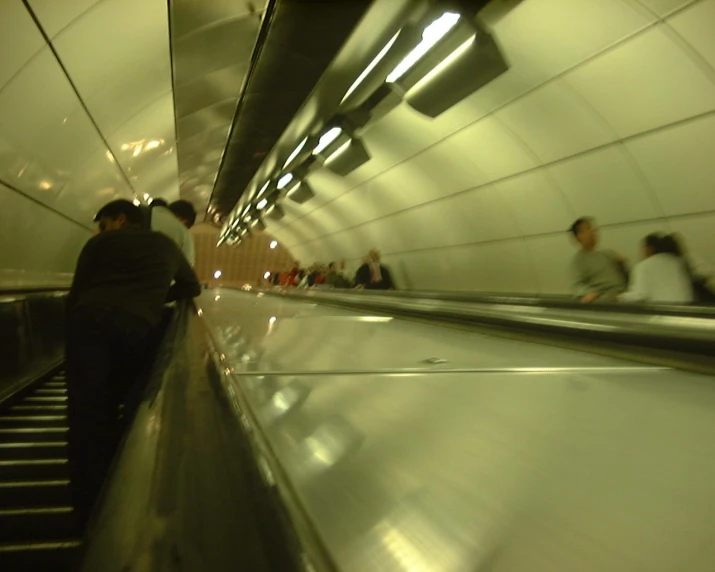 people riding down an escalator inside a subway