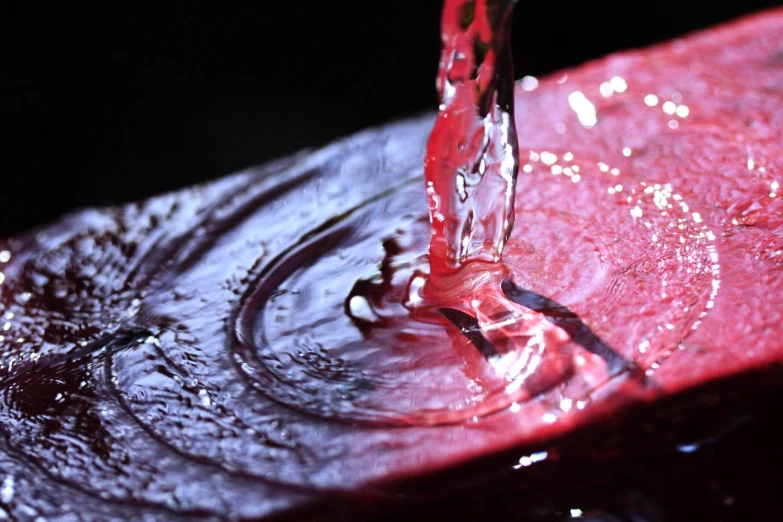 a dripping red liquid from a faucet into a sink