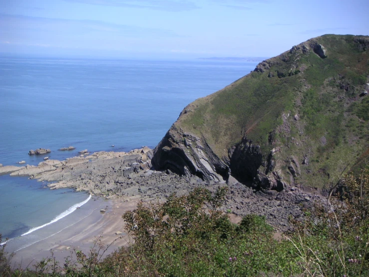 the green mountains are rising up over the ocean