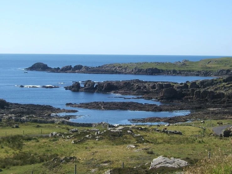 some sea water rocks and a hill and blue sky