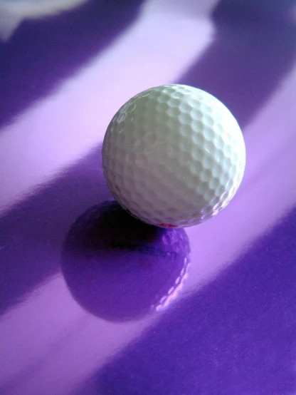 a white golf ball sitting on top of a purple table