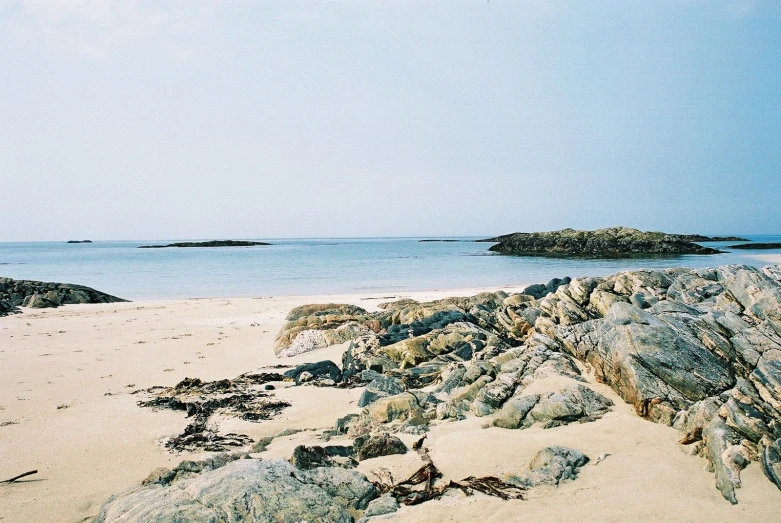 some big rocks on the side of a sandy beach