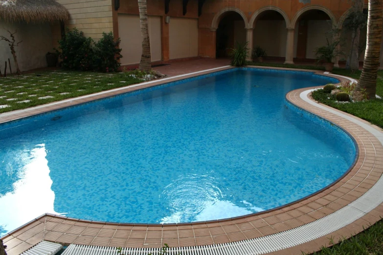 an oval shaped swimming pool surrounded by grass