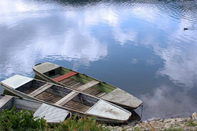 an old row boat sitting next to a large body of water