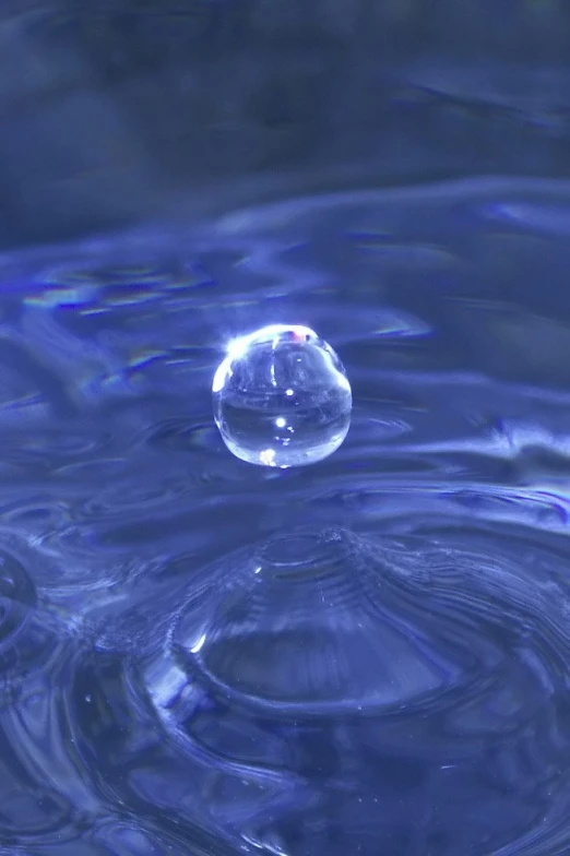 a water drop is above the surface of a blue surface