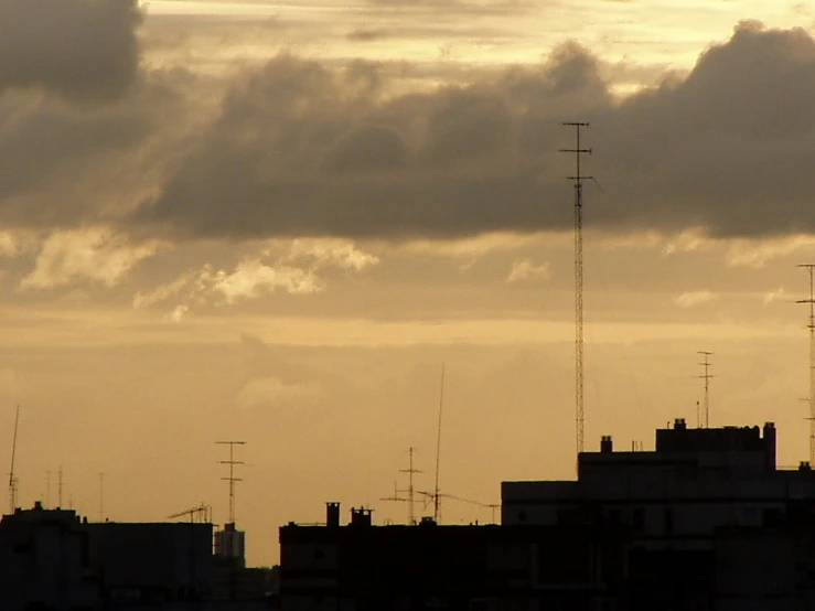 the city buildings are all silhouetted against a cloudy sky