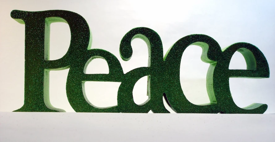 a metal sculpture with green letters on the wall