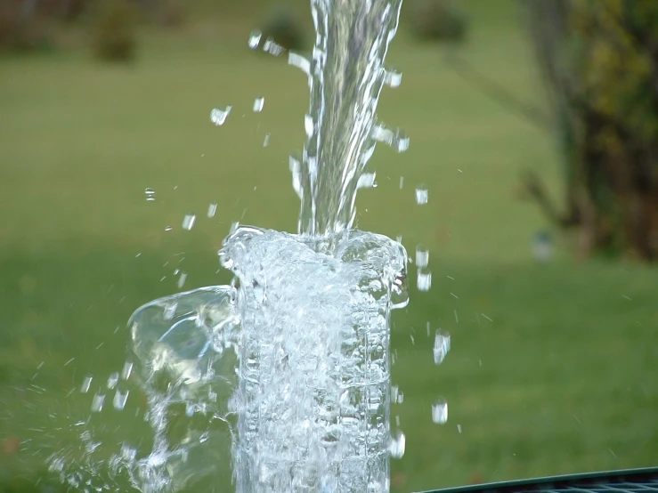 a glass with water coming out of it sitting on a table