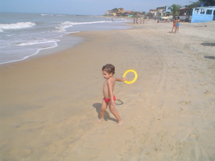 a  walking on a beach with a frisbee