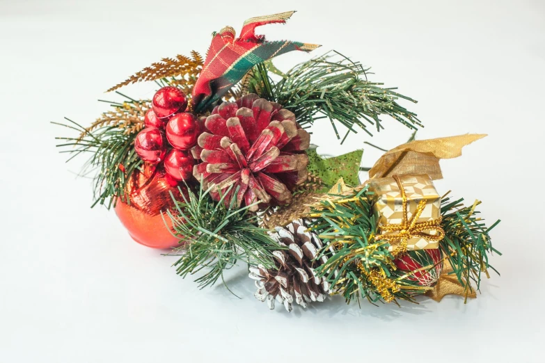 a pine cone, pine cones, evergreen leaves and bow in a vase