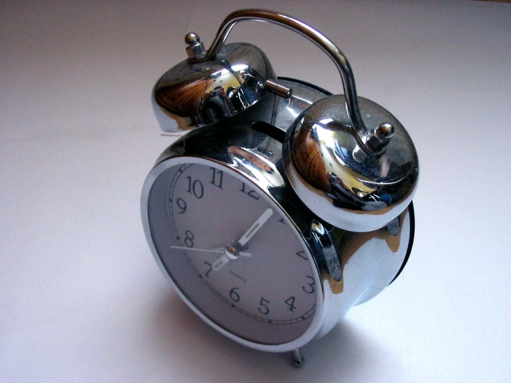 an alarm clock on a white table with a kettle