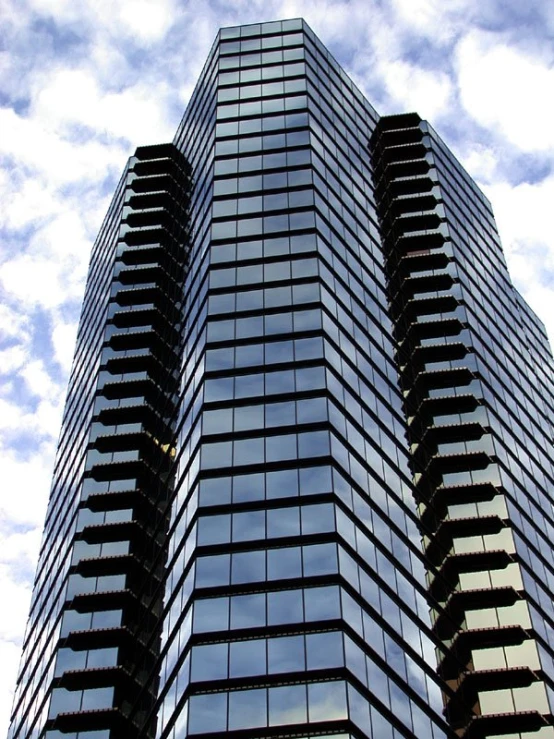 the top of a glass office building with cloudy sky