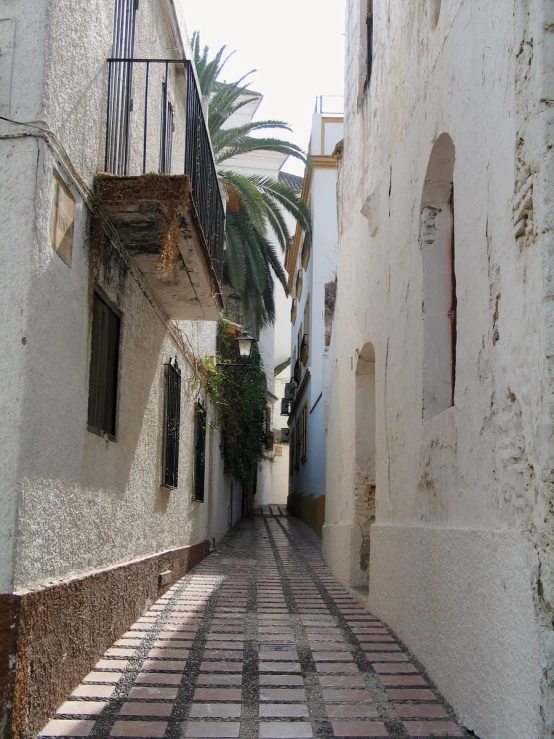 a narrow cobbled street with white walls and small balconies