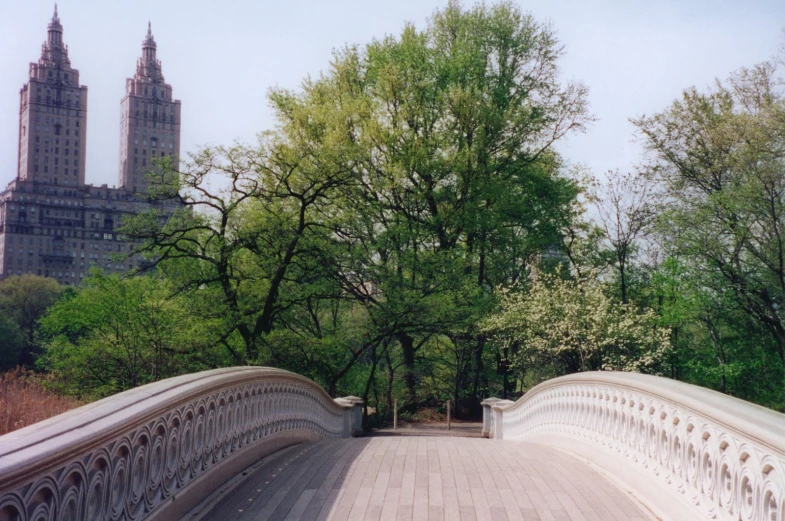 a wooden bridge crosses over a road in a city park