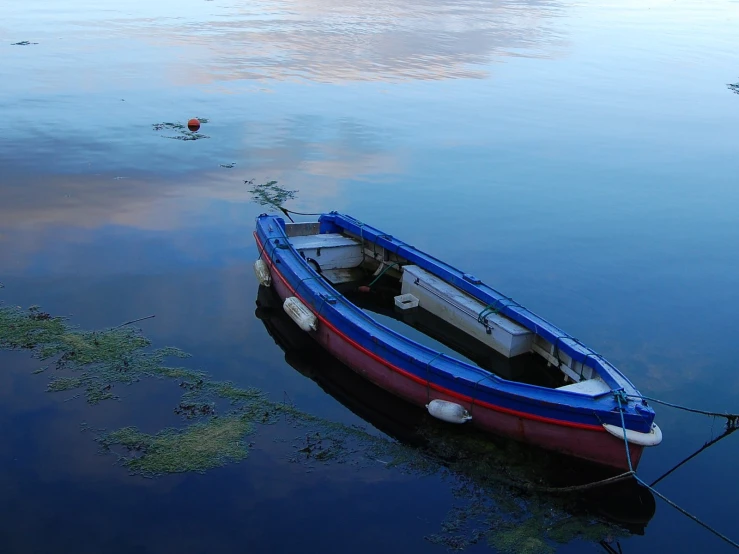 a boat sits docked in the still water of a lake