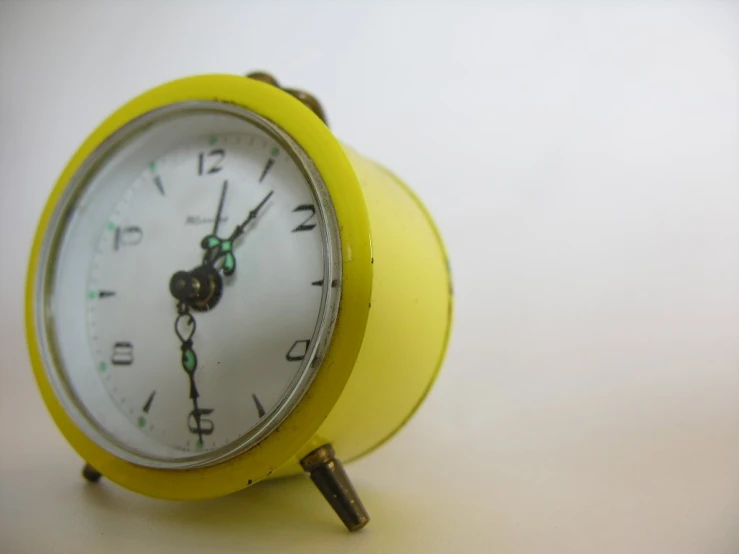 yellow clock sitting on table, with numbers on face