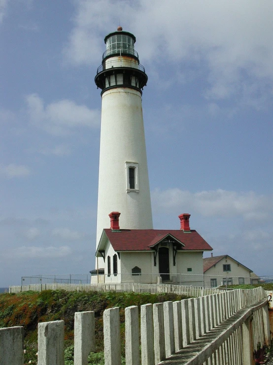 a lighthouse with a small red roof on top of a cliff
