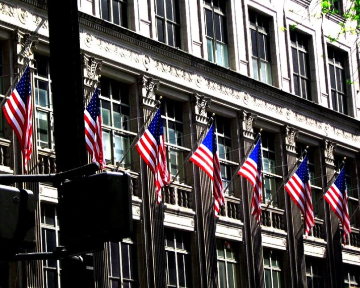 american flags blowing in the breeze against a tall building