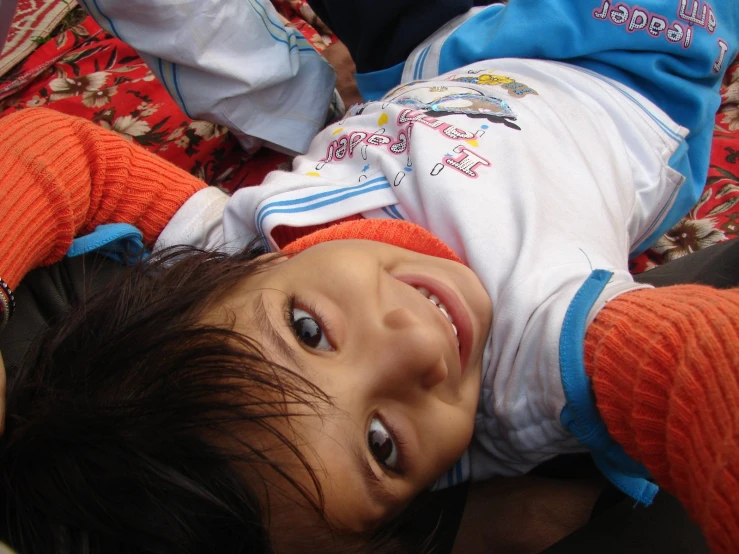 a little boy laying down in an orange blanket