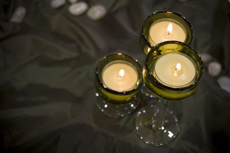 three glass candles on a table with a black tablecloth