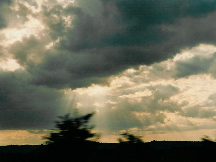 the sun shines through the clouds over a field