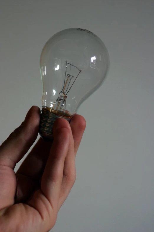 a light bulb is in someones hand against a white background