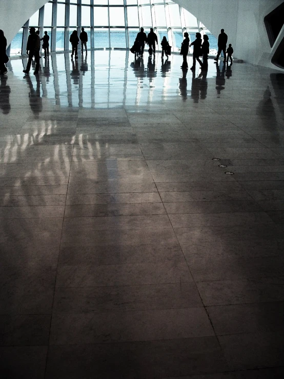 several people standing inside a large building near a clock