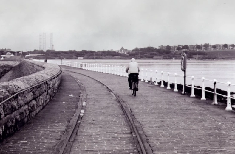 man on bike riding down the path with waterway in background