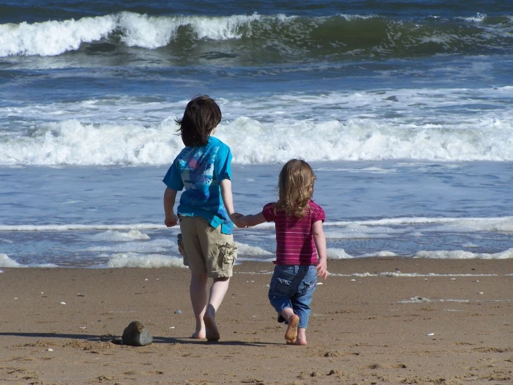 a couple of little girls running on the beach