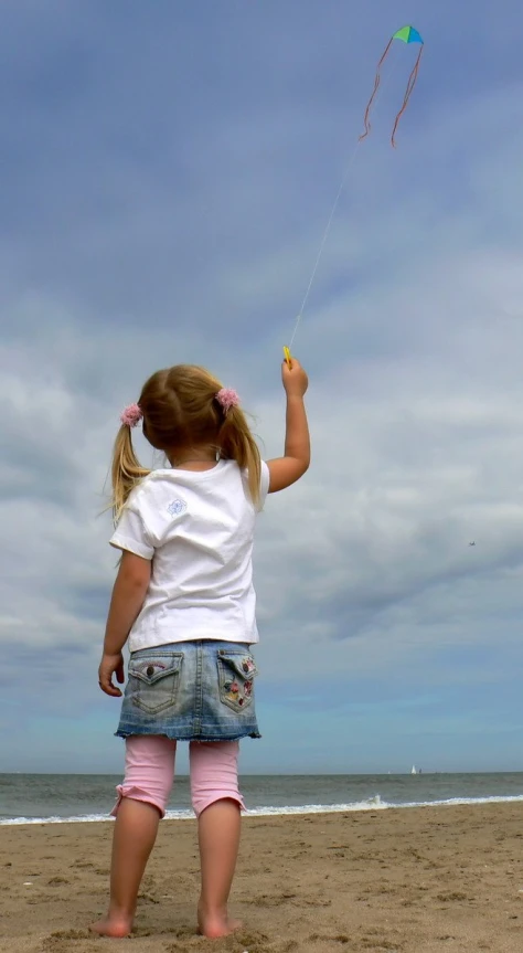 a little girl flying a kite on the beach