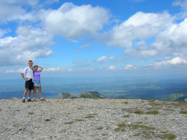 a man and woman standing on top of a mountain