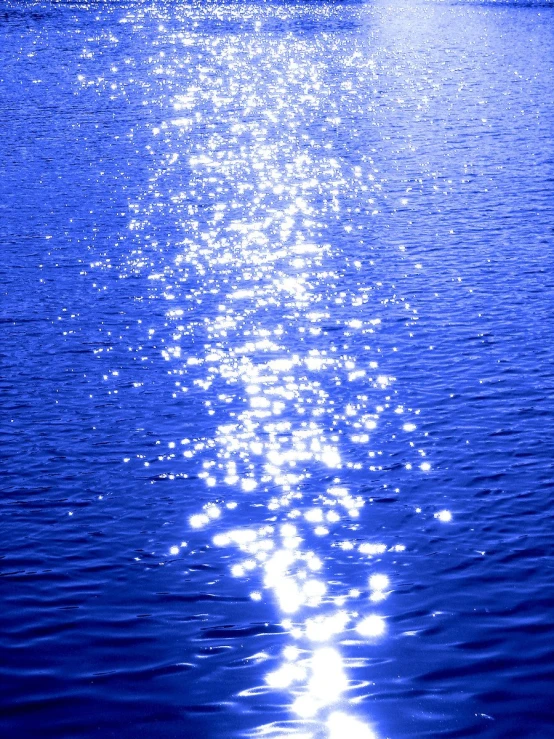 the backlight of a full moon shines over water