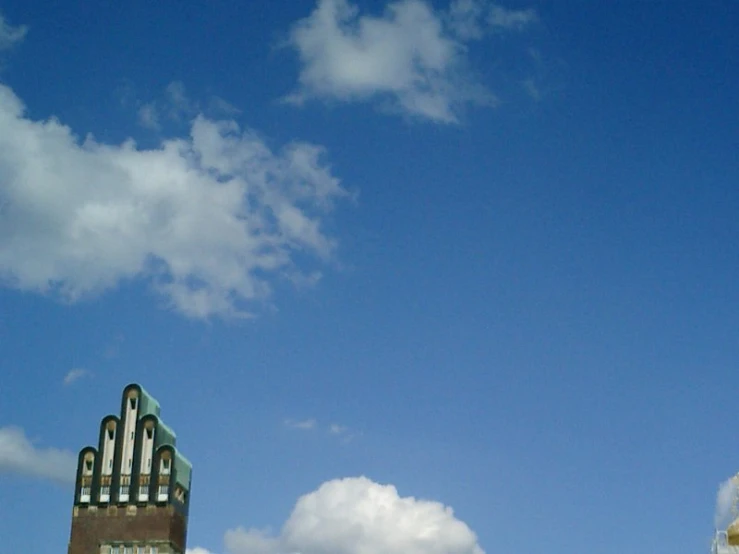 a tall, shiny, white tower building next to a cloudy blue sky
