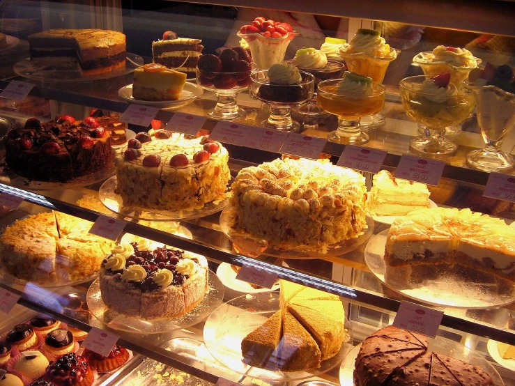 many types of cakes in a bakery glass case