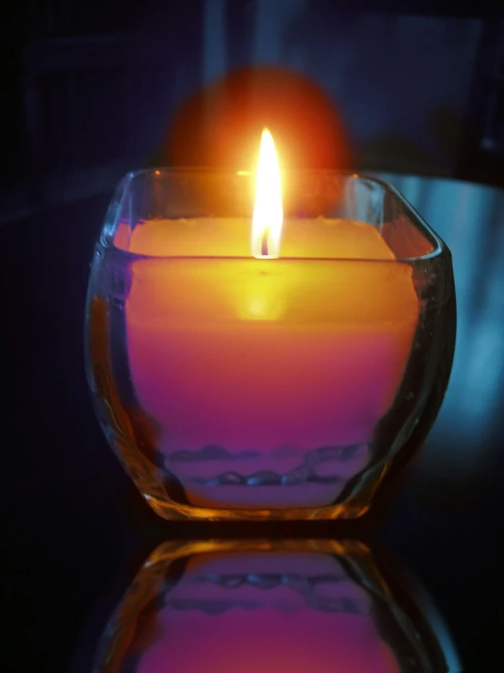 a lit candle sits in the middle of a glass bowl